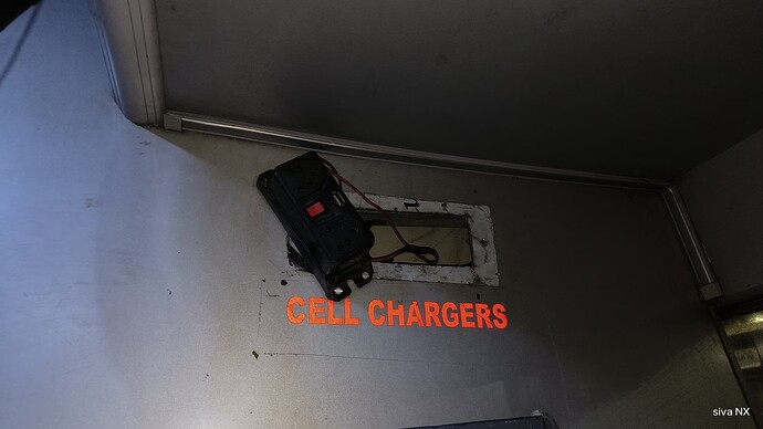 A sign labeled "Cell Chargers" hangs above a power outlet inside a vehicle. (Captioned by AI)