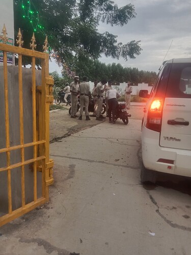 A group of police officers stand by a white SUV while a man on a motorbike looks on. (Captioned by AI)