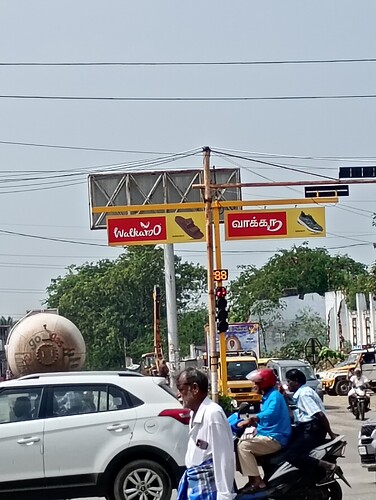 A busy intersection features traffic, billboards, and a large gas tanker. (Captioned by AI)