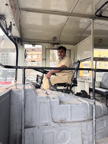 A bus driver sits in the driver's seat of an old bus. (Captioned by AI)